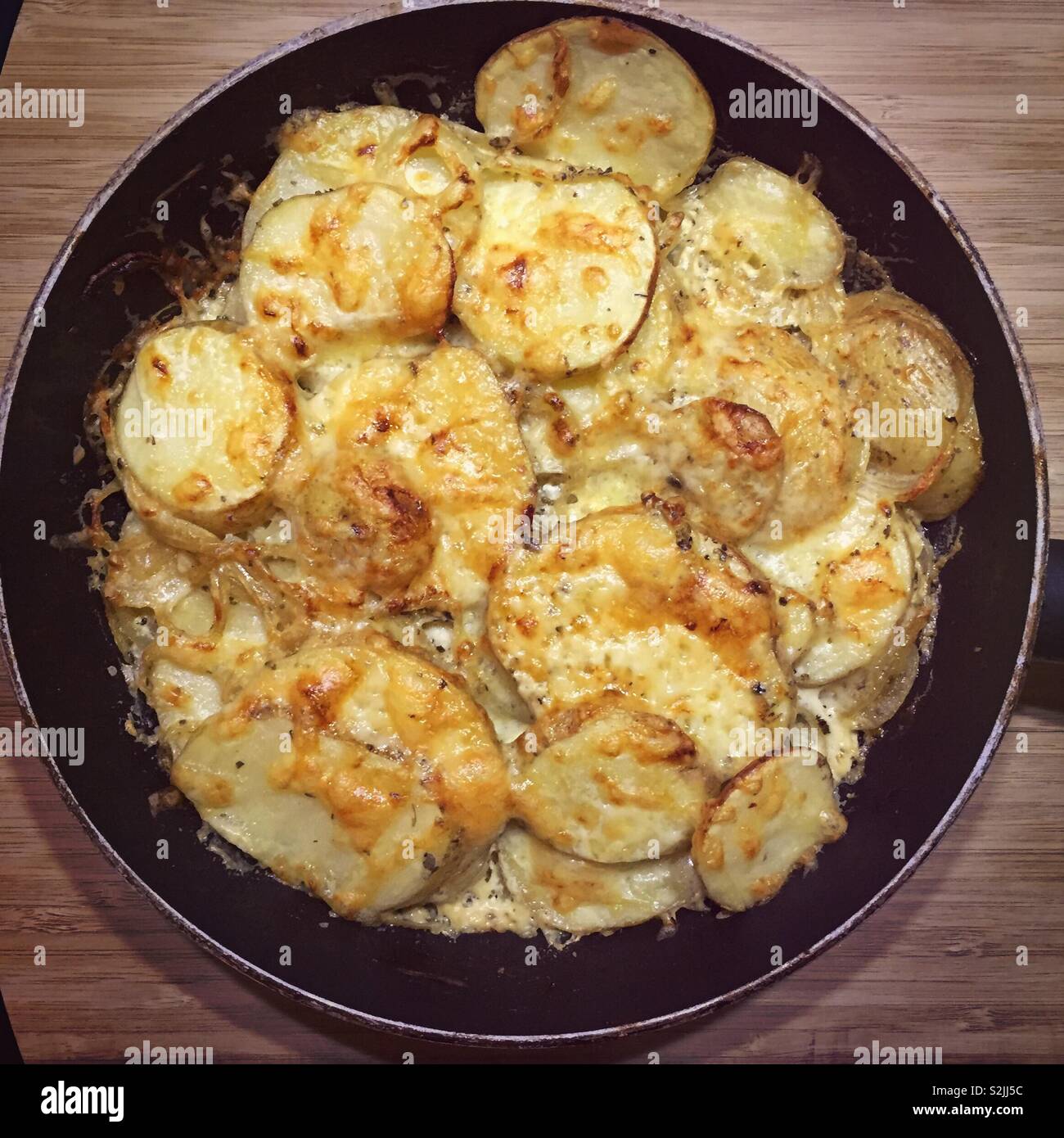 French boulangere potatoes.  Crisped and golden roasted sliced potatoes.  Cream onion cheese stick herbs.  Have it your way for Sunday lunch or posh home cooking - Smartphone Captured Stock Image
