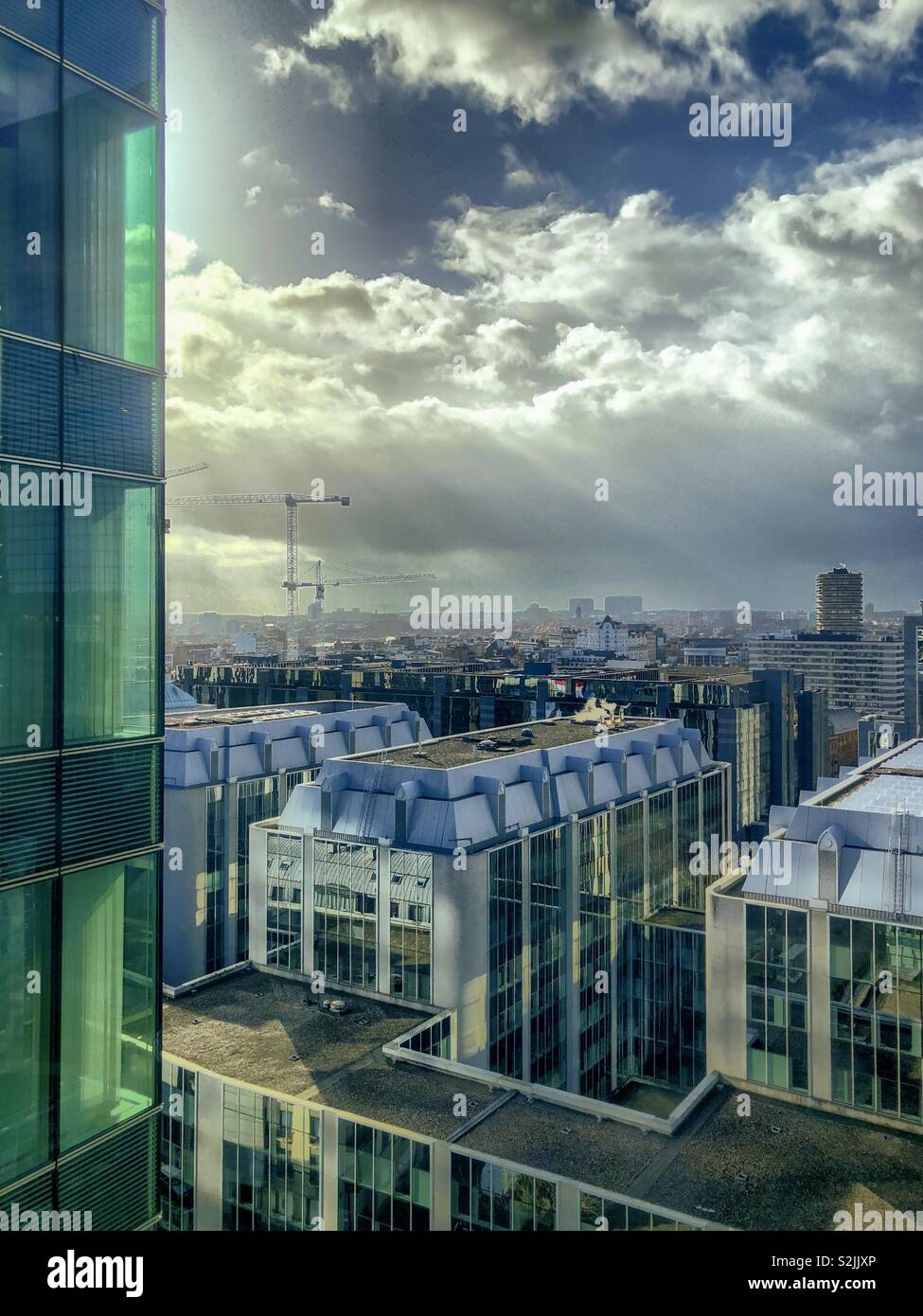Rays of sun breaking through the thick clouds over the offices of the business district of the city of Brussels Stock Photo