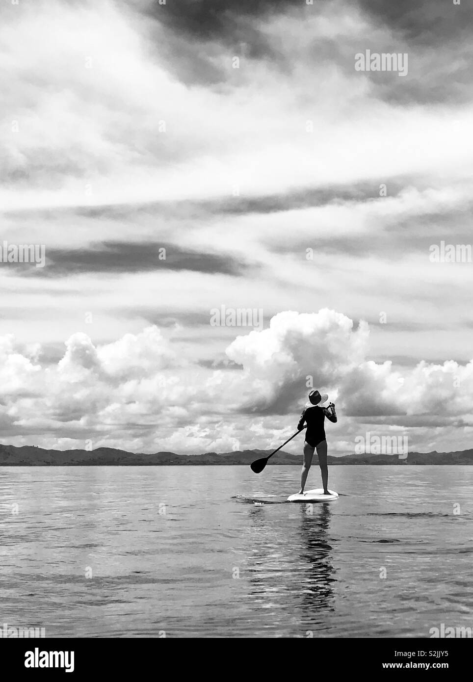 A young women stand up paddles. Tavarua, Fiji. Stock Photo