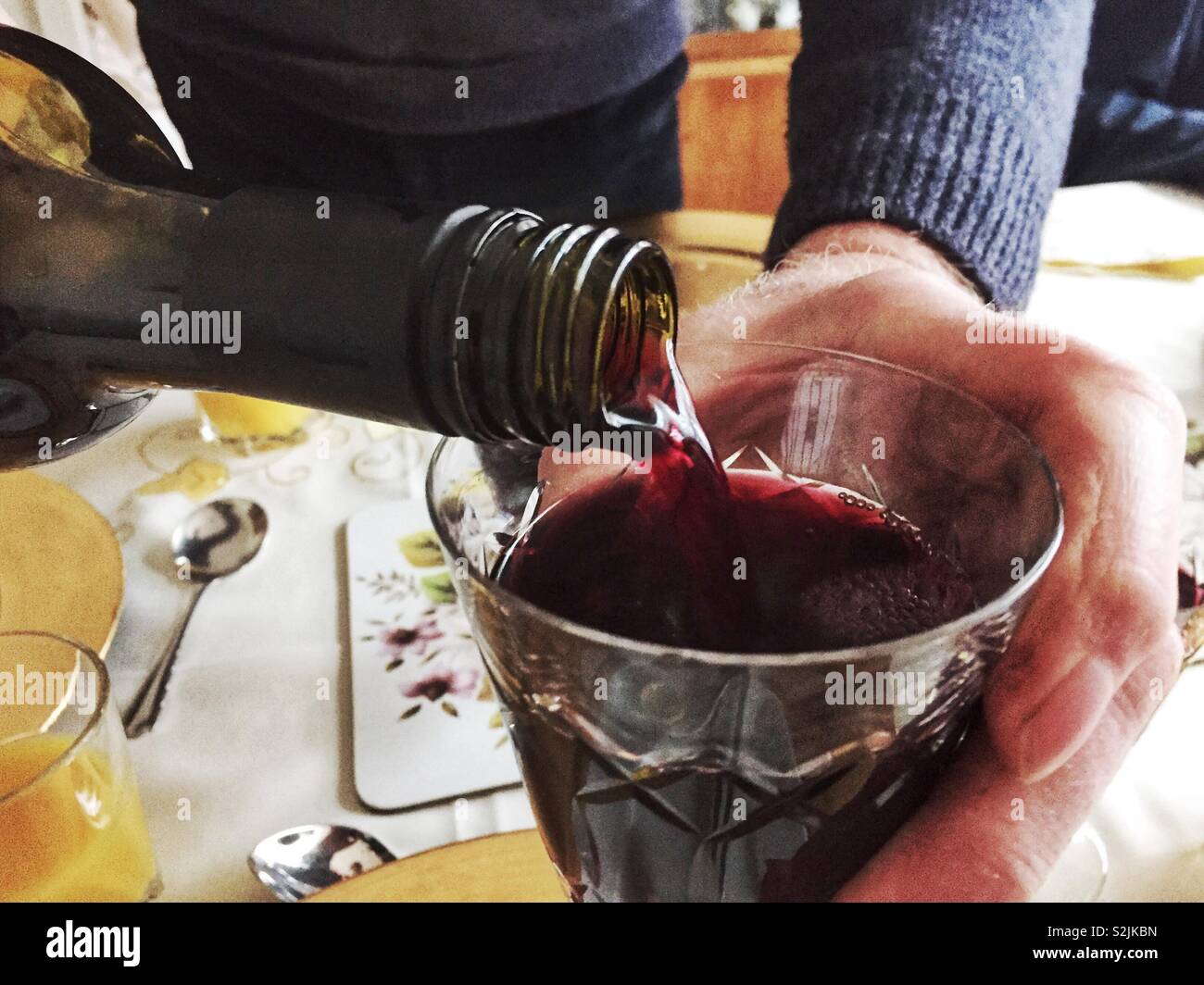 A man pours a glass of red wine. - Smartphone Captured Stock Image