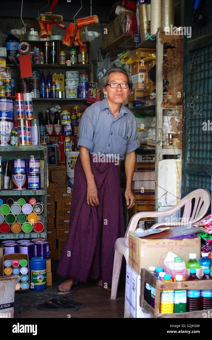 Portrait of a burmese man. Midaged man in Myanmar, posing for the picture in his tiny shop for spray colors and paint in Yangon, Burma. Stock Photo