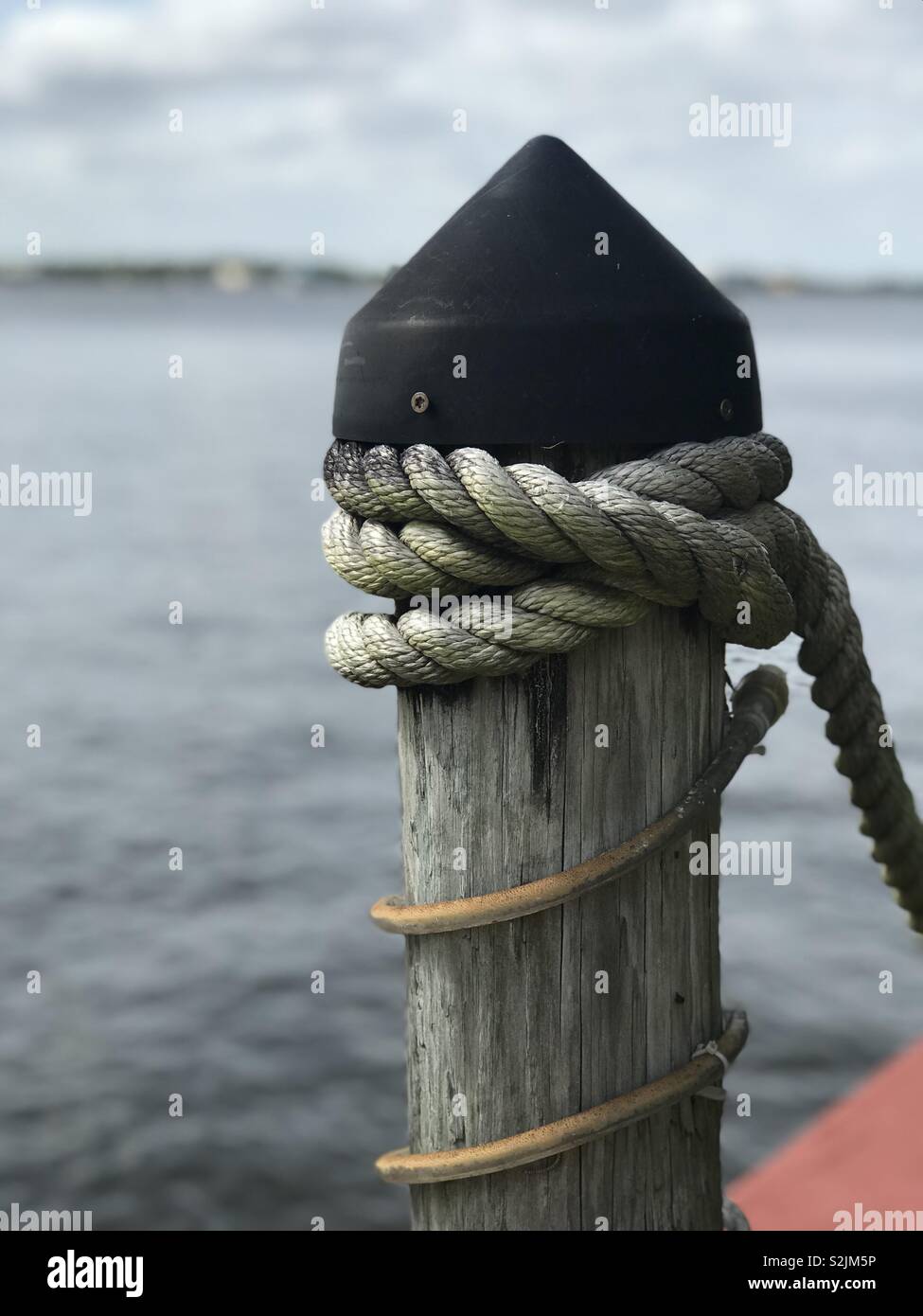 Boat dock post with rope attached Stock Photo - Alamy