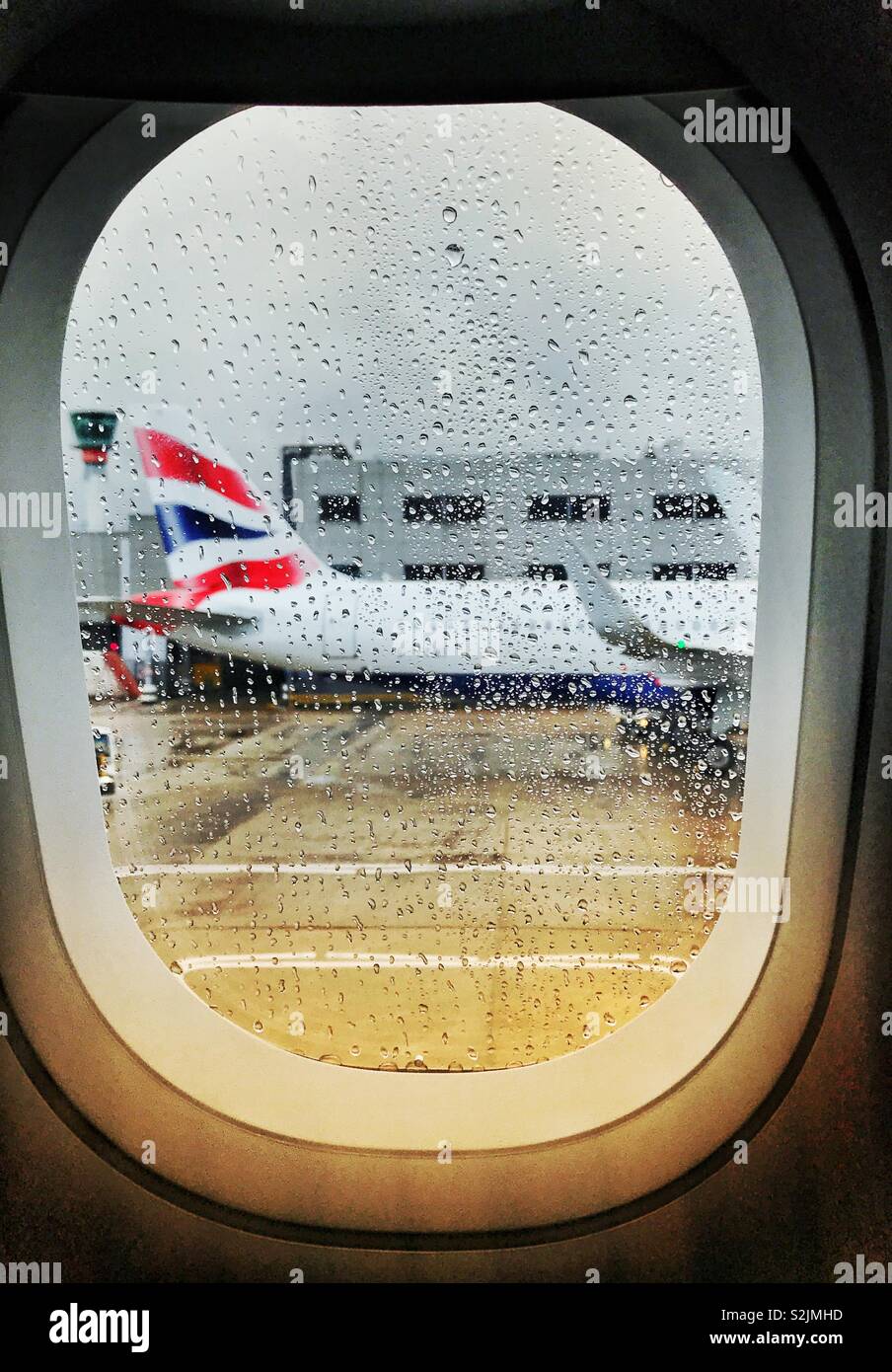 Raindrops on the window of a plane with another airliner blurred in the background - Smartphone Captured Stock Image
