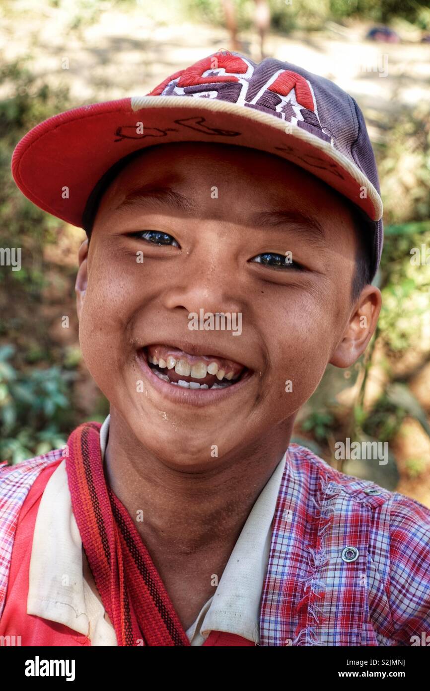 Portrait of a young burmese boy laughing, smiling into the camera. In Myanmar on a sunny morning. Stock Photo