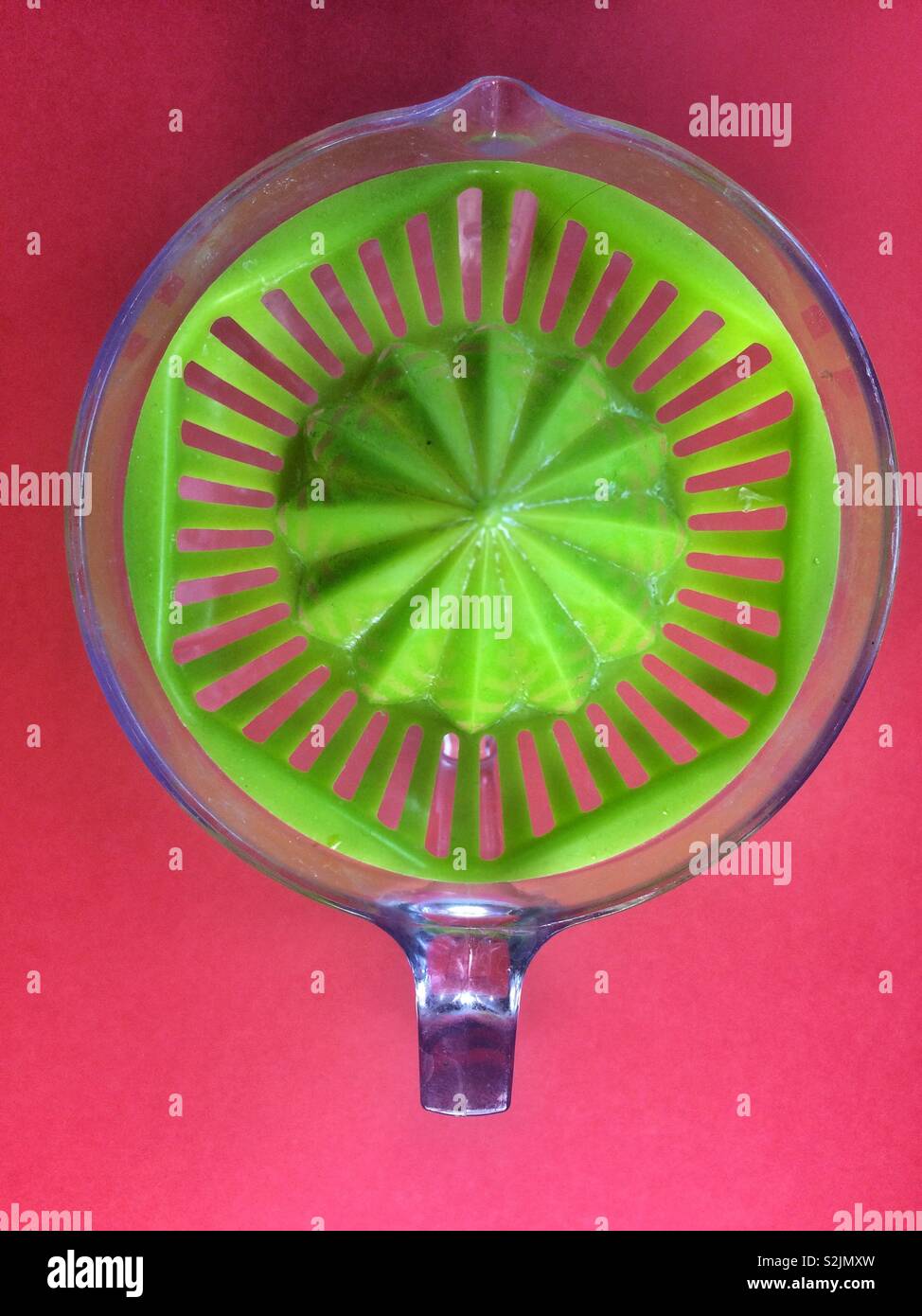 Green manual juice maker on red background - Smartphone Captured Stock Image