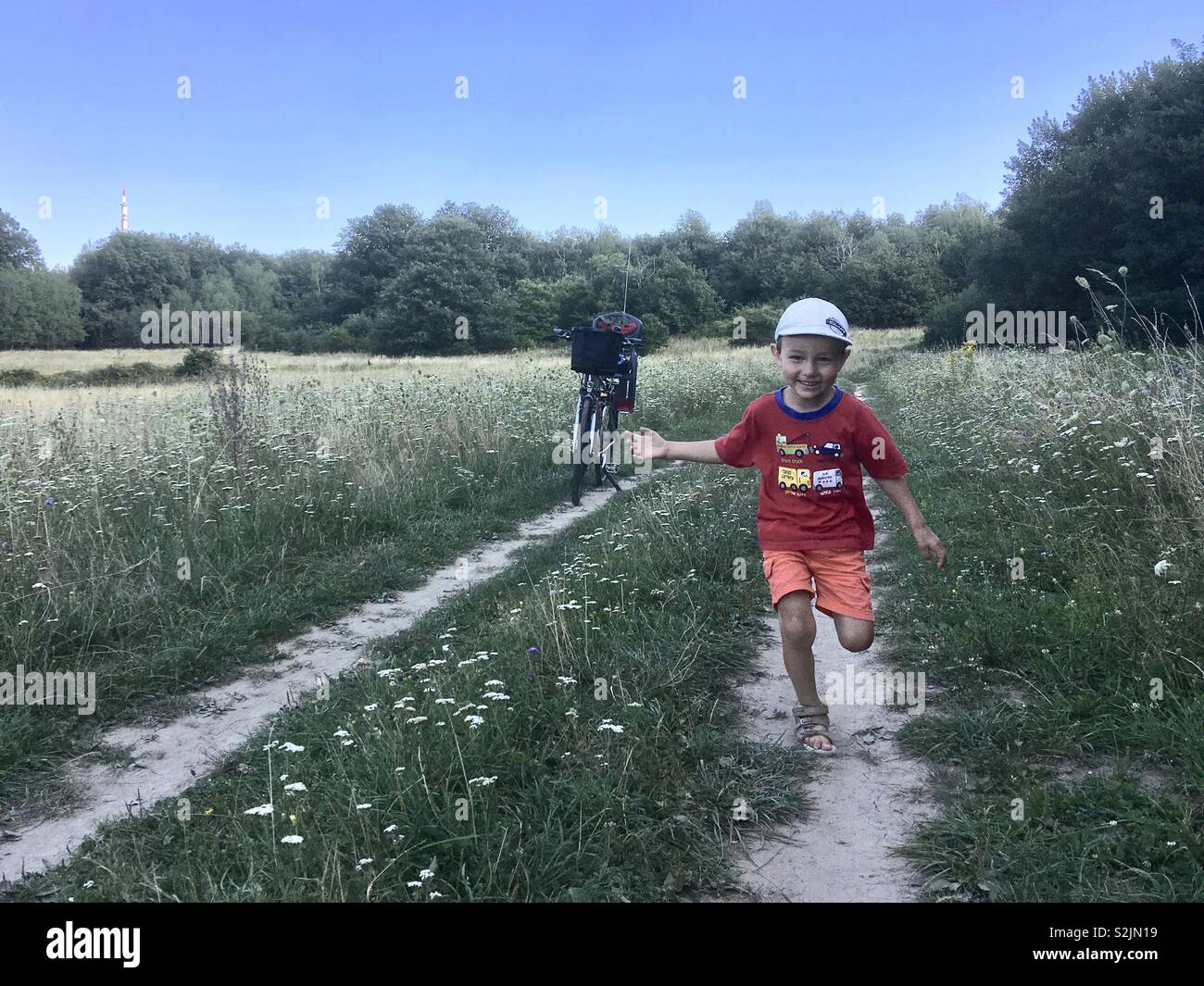 Boy child running towards camera on footpath across meadow - Smartphone Captured Stock Image