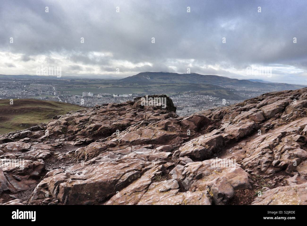 View across rocks on Arthurs Seat Edinburgh towards the Pentland Hills Stock Photo