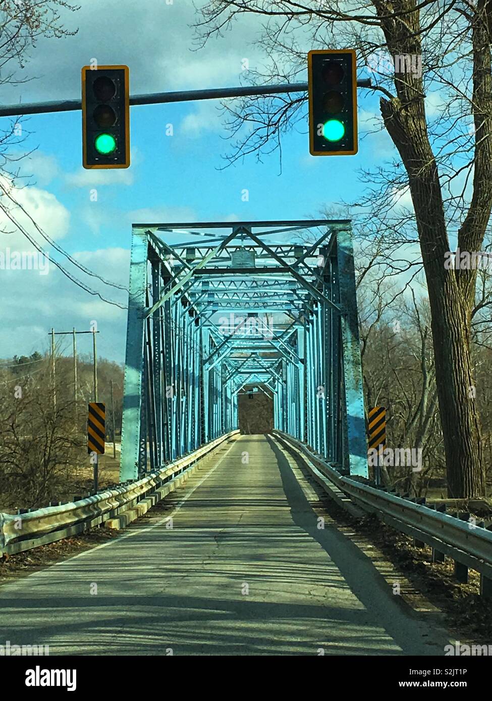 Bridge with one lane and a stoplight that allows only one way traffic to cross the river. Stock Photo