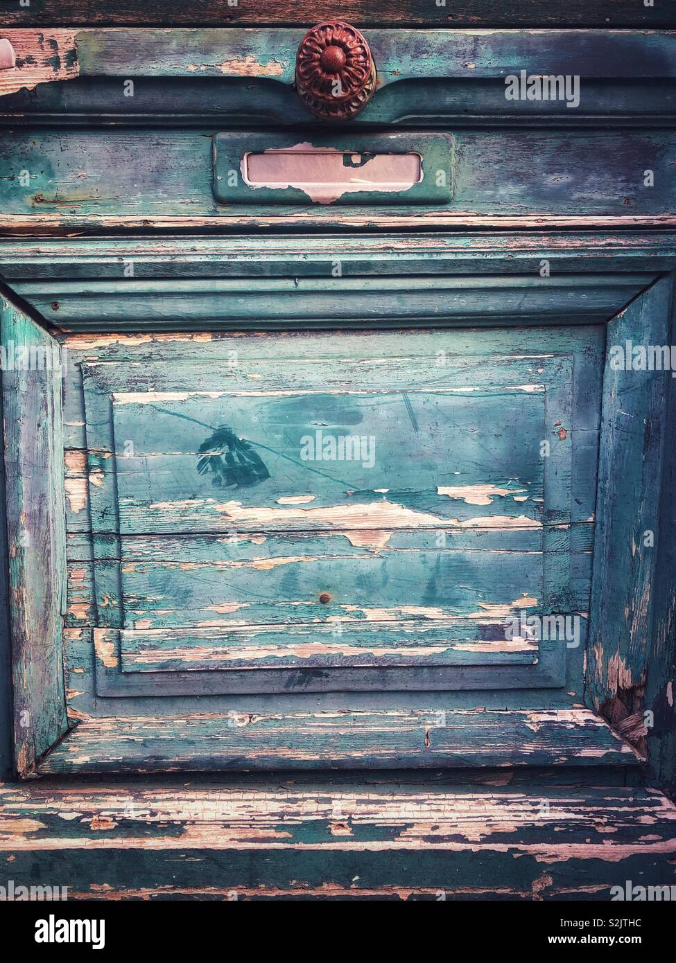 Part of an old green door with peeling paint - Smartphone Captured Stock Image