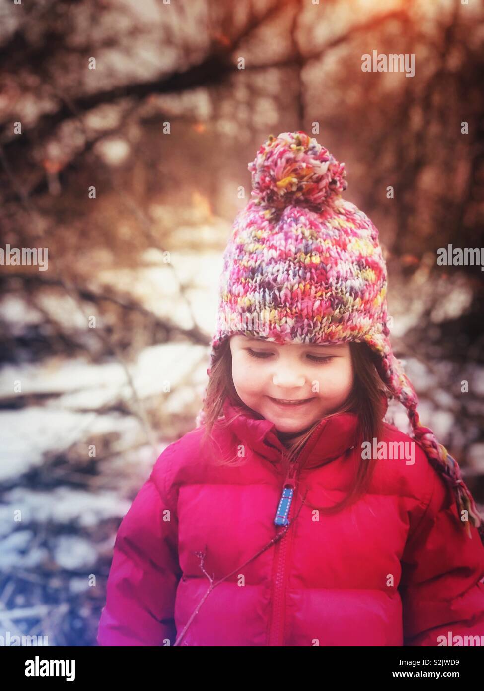 Candid portrait of happy girl looking down in forest - Smartphone Captured Stock Image
