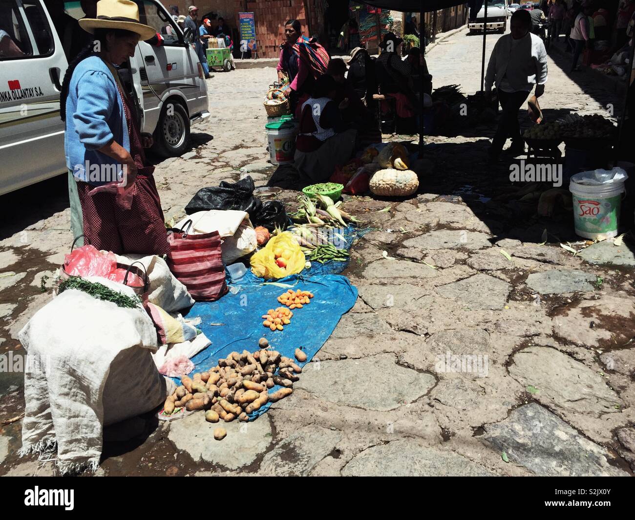 Indigenous woman man sells potatoes on a street near Ollantaytambo town market in Peru - Smartphone Captured Stock Image