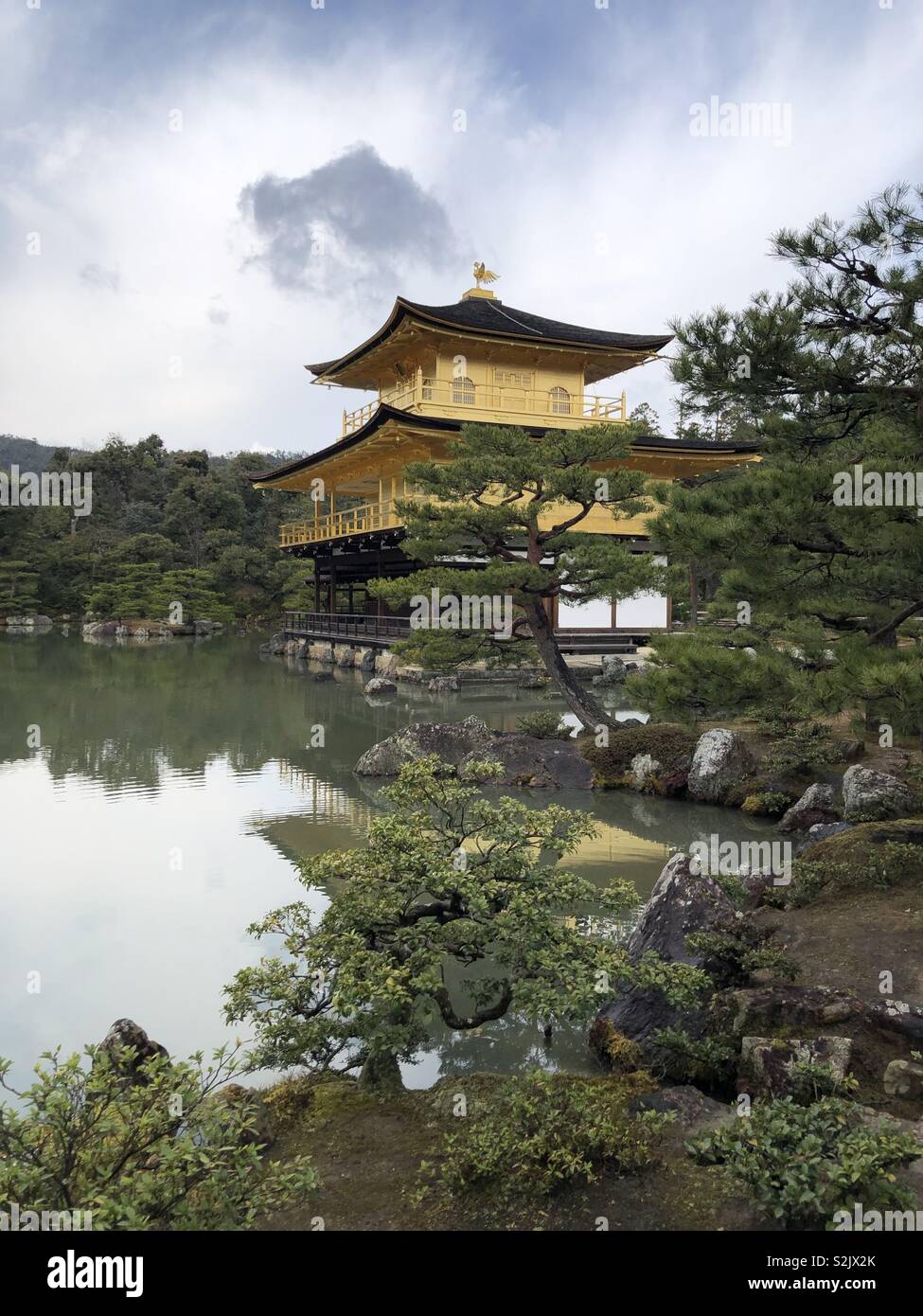 Kinkaku-ji (金閣寺, literally 'Temple of the Golden Pavilion'), officially named Rokuon-ji (鹿苑寺, literally 'Deer Garden Temple'), is a Zen Buddhist temple in Kyoto, Japan. Stock Photo