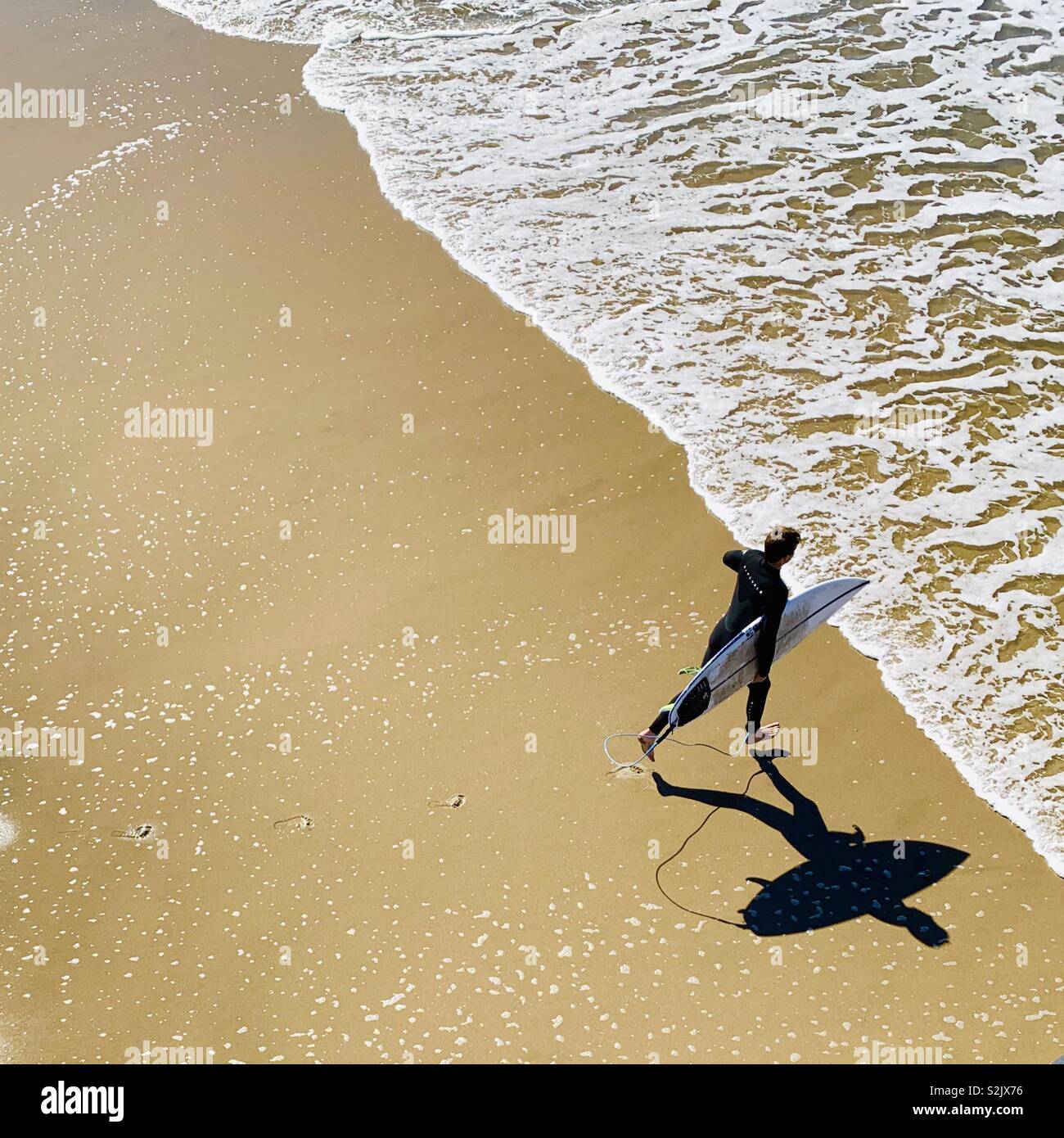 Male surfer running into the water to surf. Manhattan Beach, California USA. - Smartphone Captured Stock Image