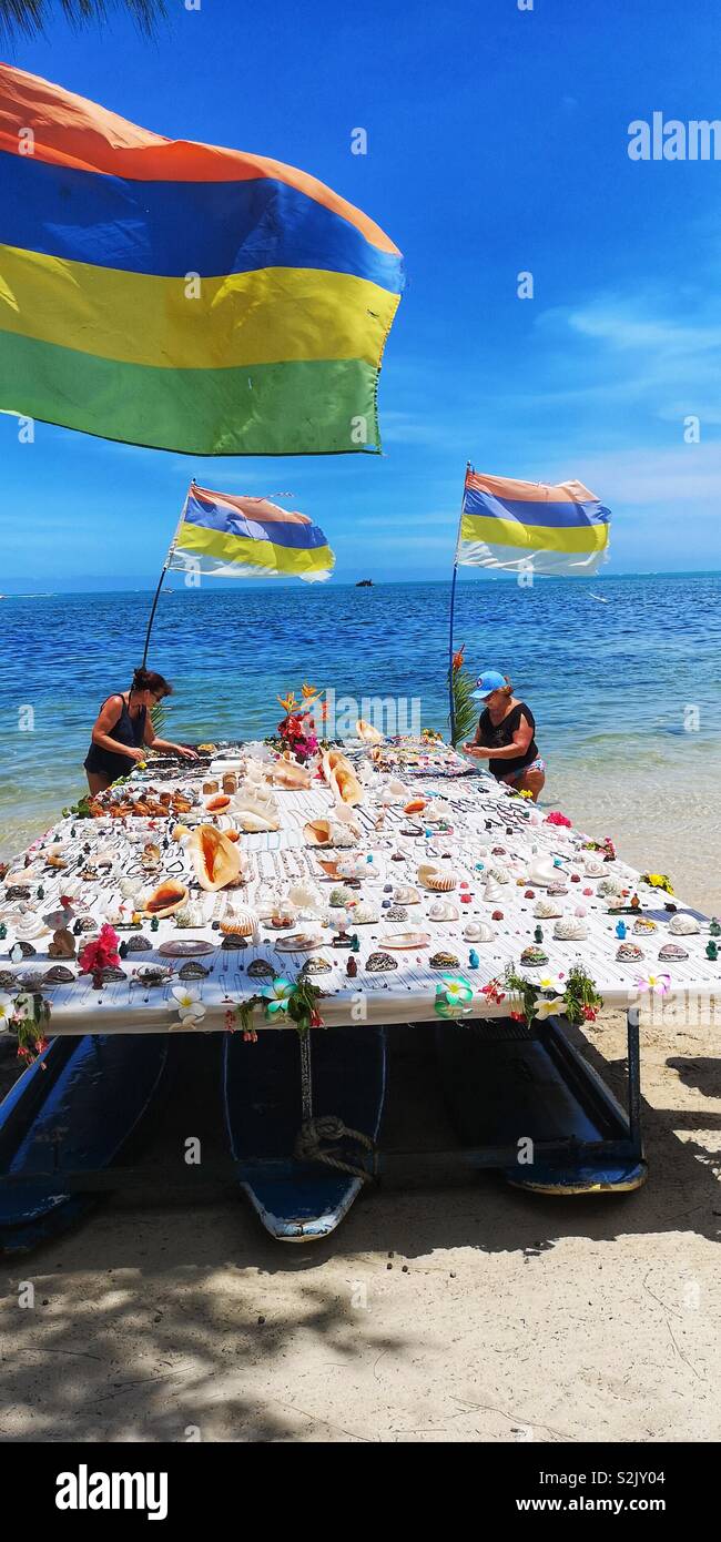 Two ladies looking for the shells and homemade accessories that are displayed on the beach for sale Stock Photo