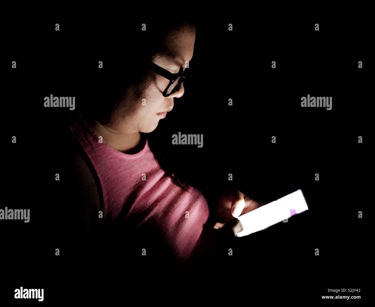 Lady using her smartphone in the dark. Stock Photo