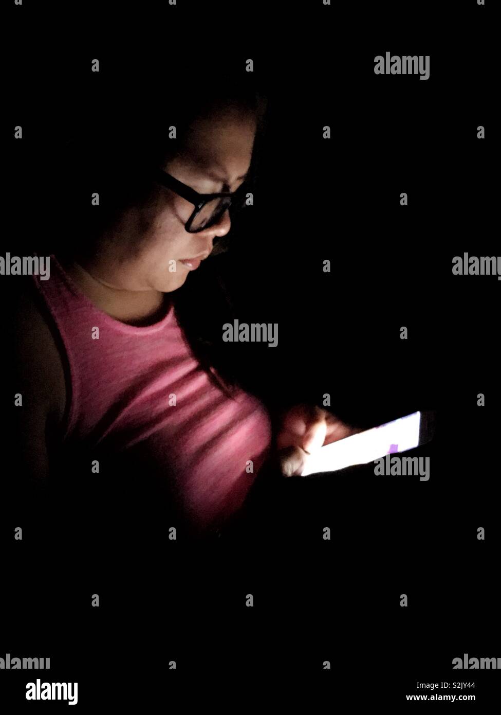 Lady using her smartphone in the dark. Stock Photo