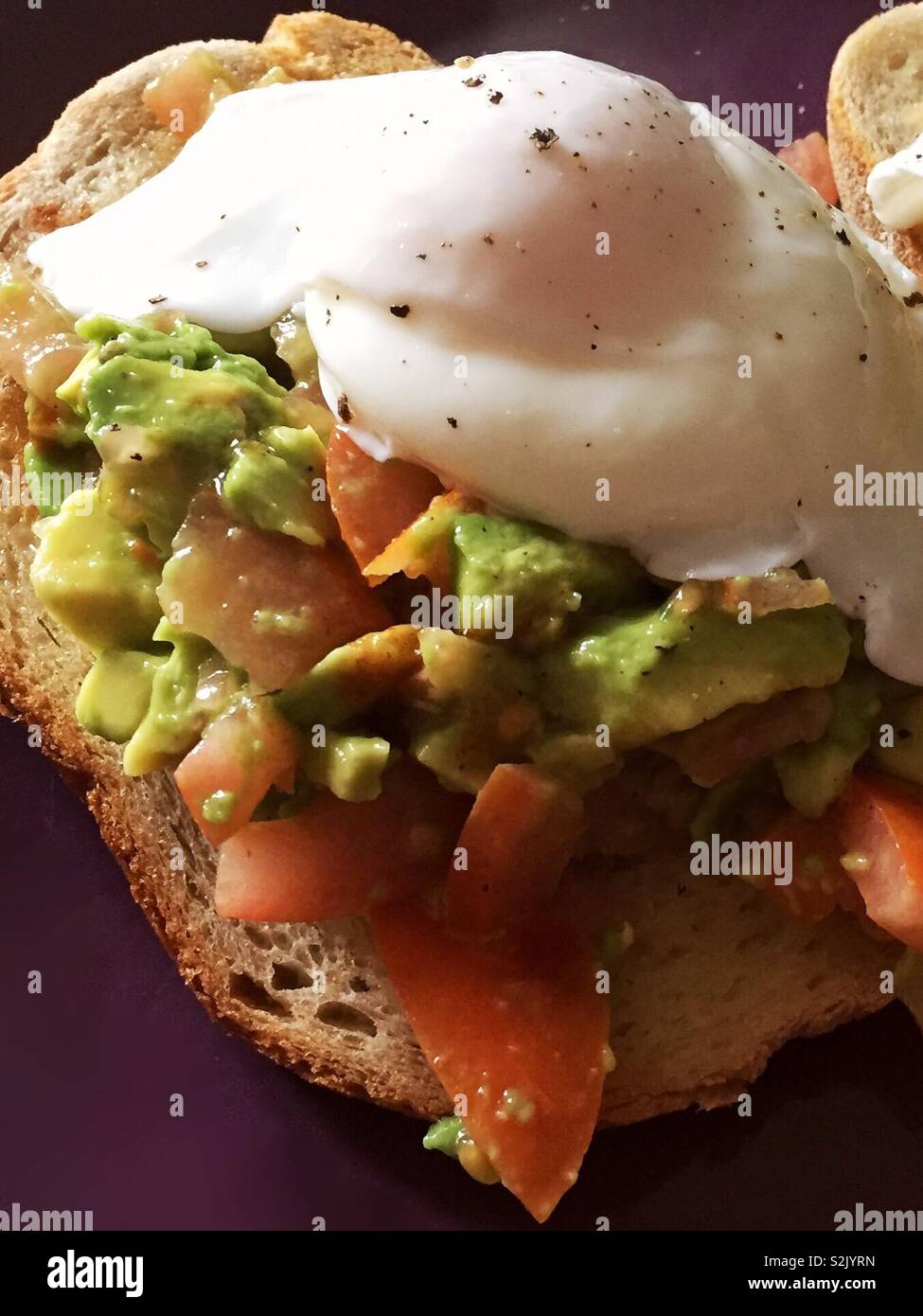 Avocado toast with poached egg on top.  Breakfast meal as a meat free alternative.  Tasty smashed avocados.  Sourdough bread - Smartphone Captured Stock Image