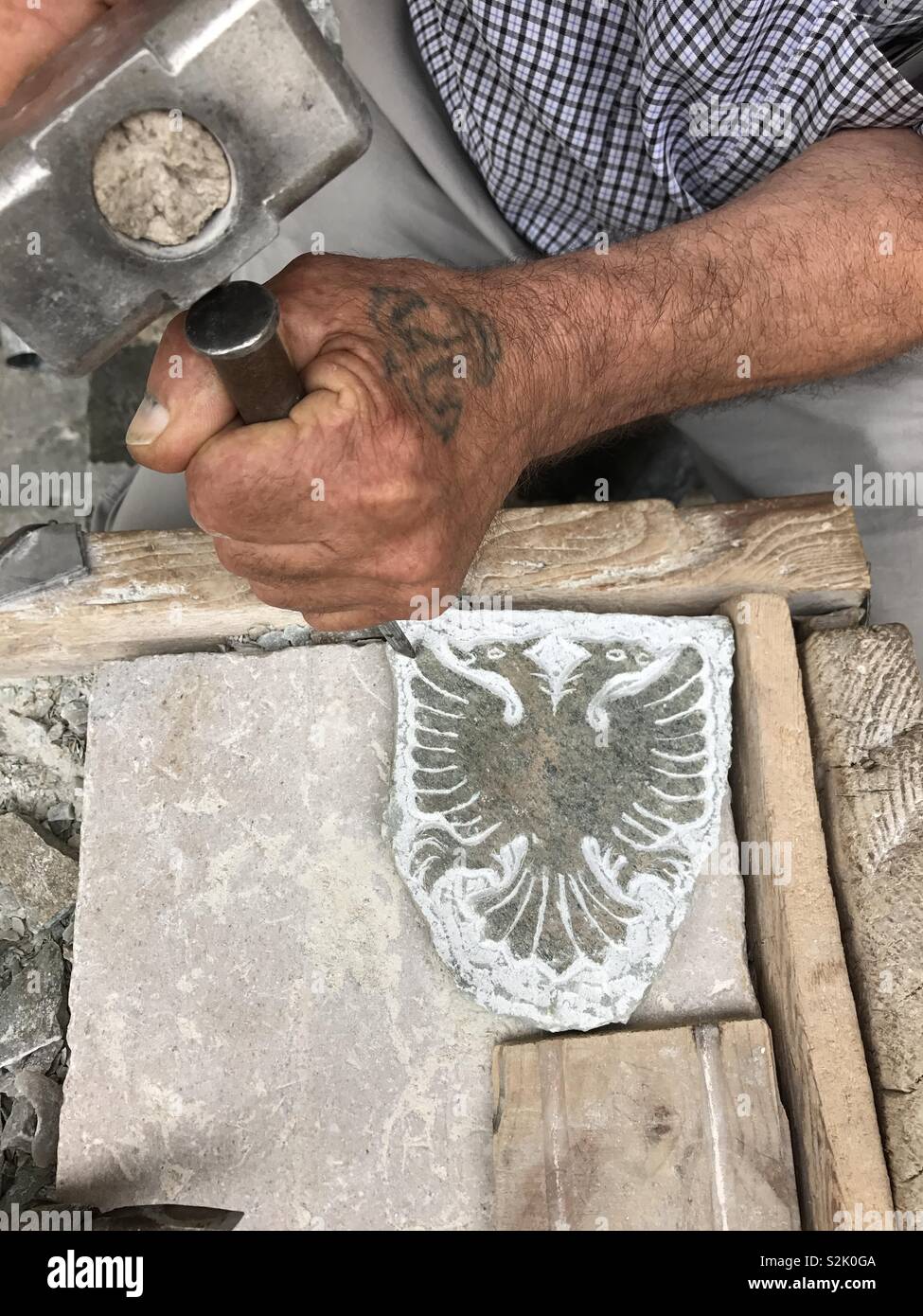 Hand of sculptor carving an eagle on a stone, symbol of the Albania country - Smartphone Captured Stock Image