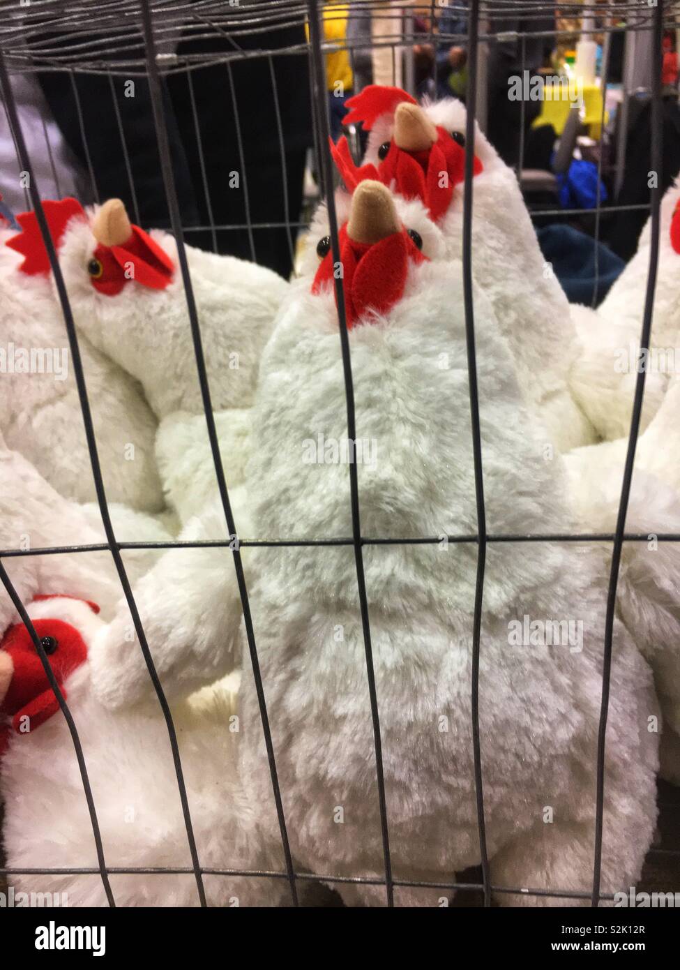 Overcrowded stuffed animal chickens standing and smushed into a wire cage that shows overcrowding of animals in cages. Stock Photo