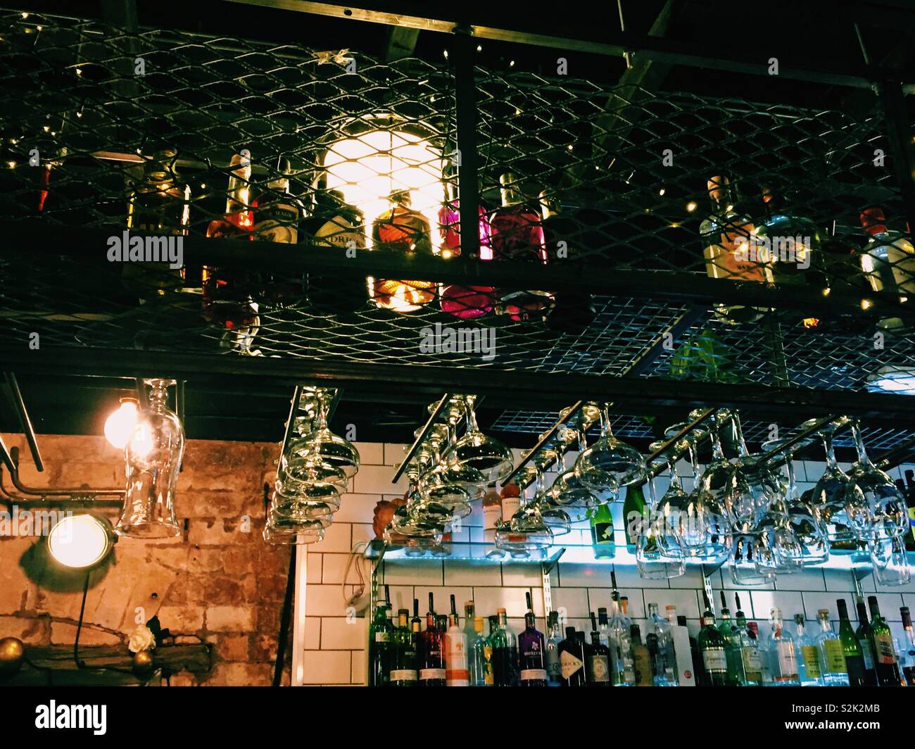 Row of colourful spirits in a city cocktail bar uk with wine glasses - Smartphone Captured Stock Image