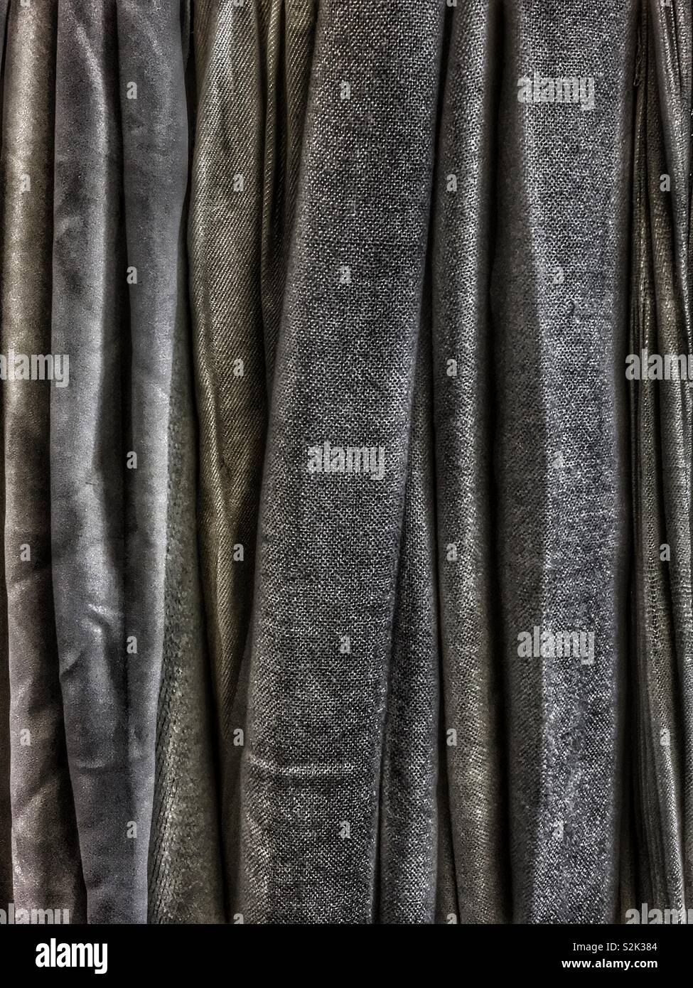 Side view of many fashionable black hued clothes hanging on a clothing rack. Stock Photo