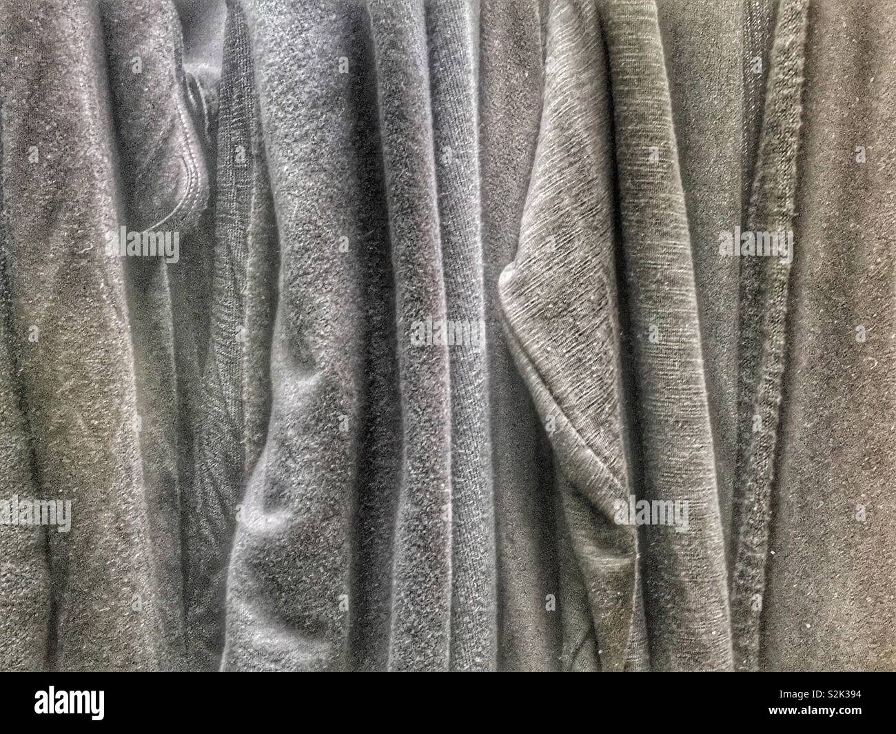 Side view of many fashionable muted grey hued clothes hanging on a clothing rack. Stock Photo