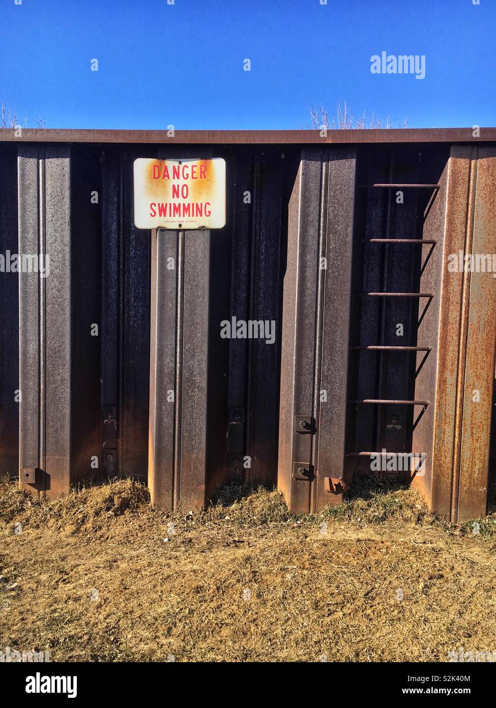 Funny sign that states “Danger No Swimming” on a steel wall, but there is no water in which to swim. - Smartphone Captured Stock Image