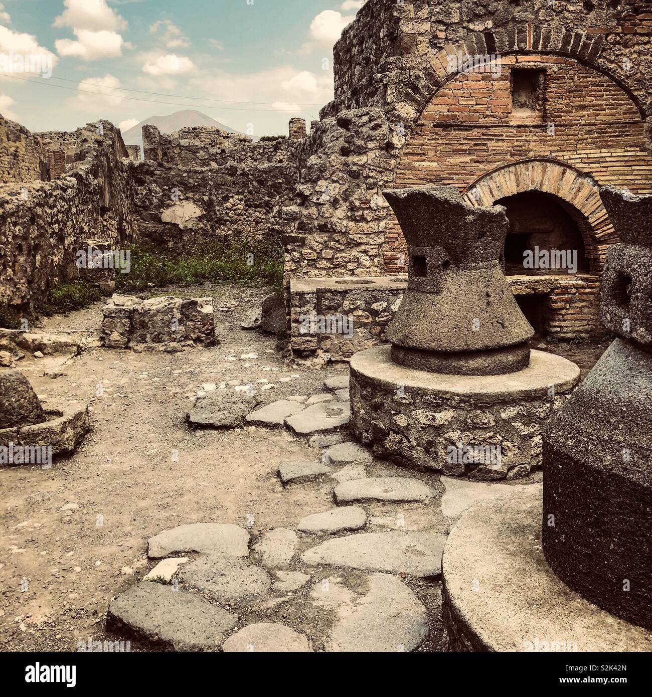 One of the original bakeries in archeological site of Pompeii, still with the mills and the oven fairly intact - the volcano Vesuvius Stock Photo