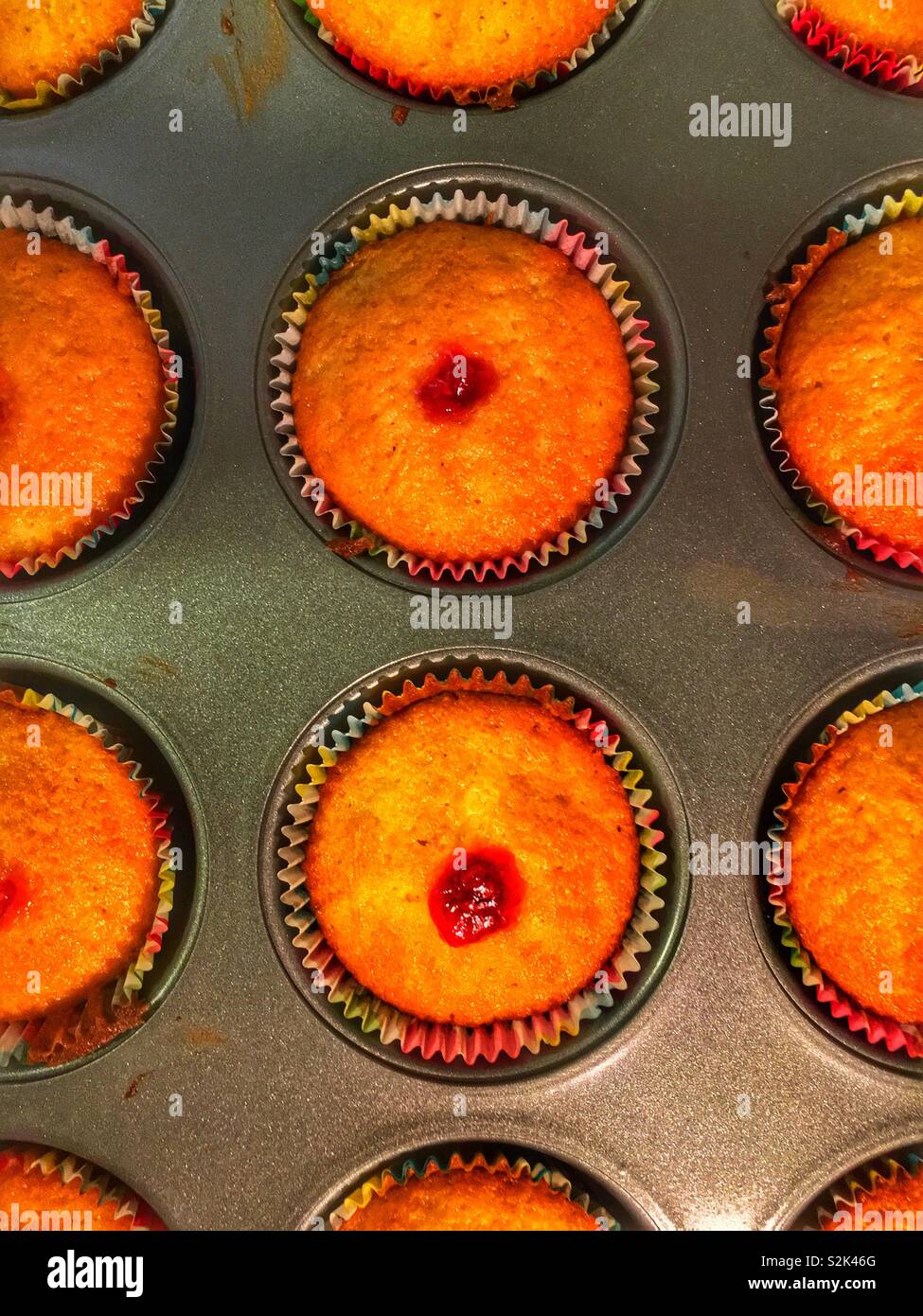 Batch of homemade cupcakes filled with raspberry filling still in the cupcake baking pan. - Smartphone Captured Stock Image