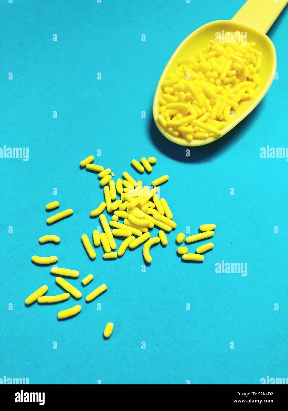 Yellow candy sprinkles on a blue background. Stock Photo