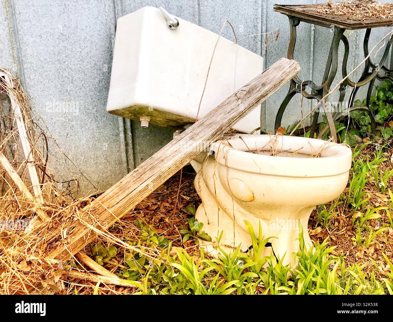 Old toilet and vintage sewing machine base sit beside metal shed - Smartphone Captured Stock Image