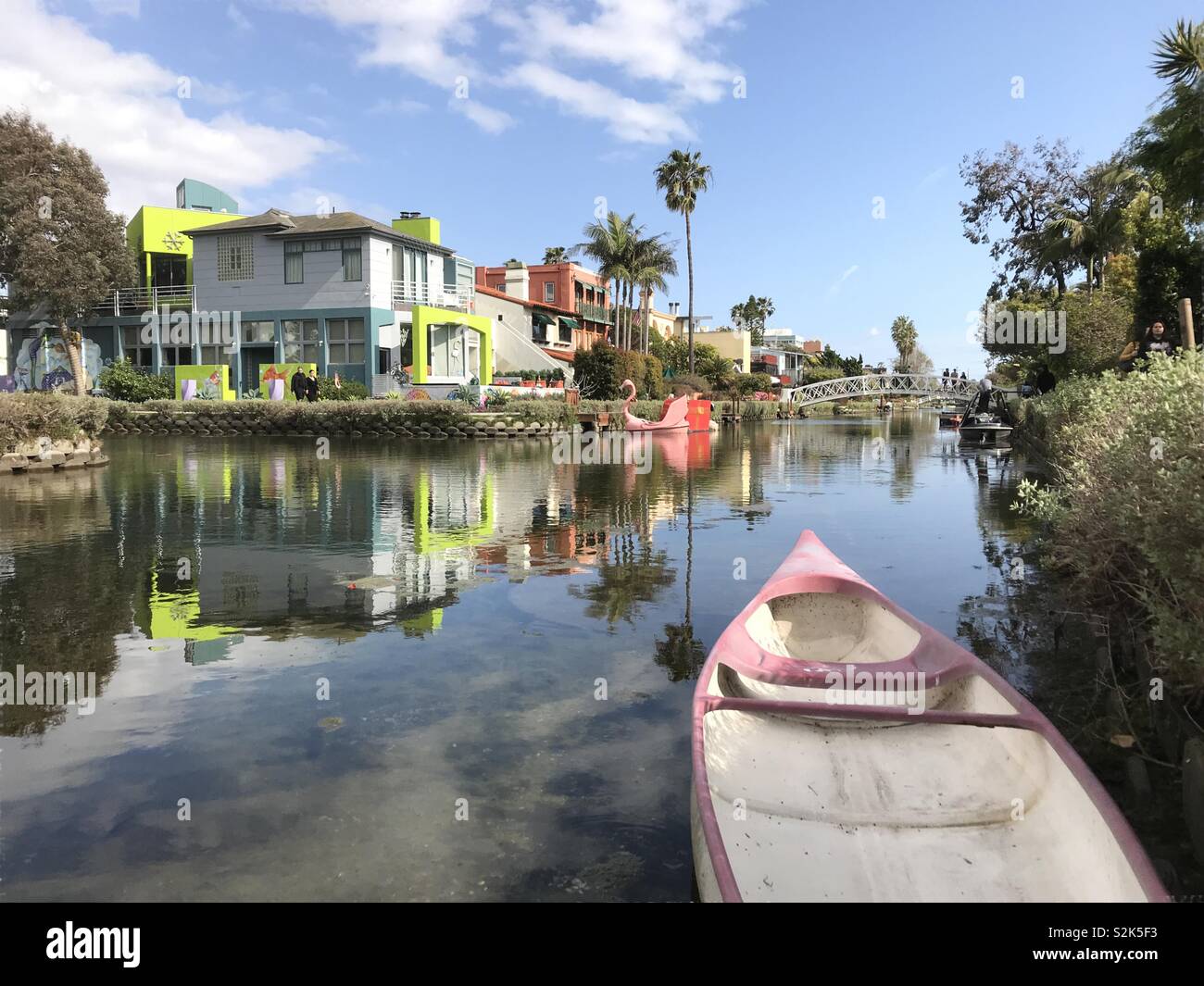 Venice, CA / USA - March 23, 2019: Small boats, modern homes, and a bridge crossing the water of the Venice Canal Historic District are shown on an afternoon day. - Smartphone Captured Stock Image
