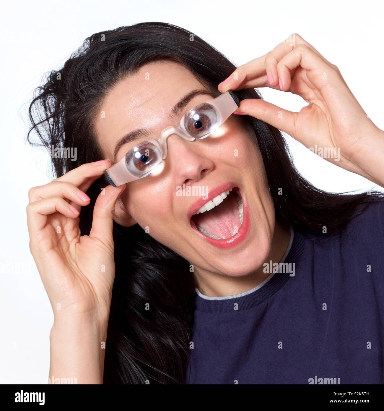 Amazed woman trying on glasses with huge magnification. - Smartphone Captured Stock Image