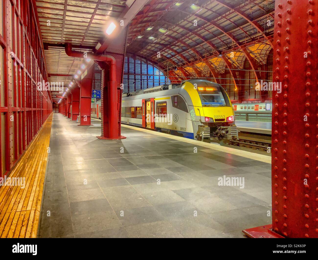 Antwerp central station in Antwerp, Belgium, as seen from the inside on the first or top platform with a train waiting on the rails at the platform, showing the structure of the old glass roof. - Smartphone Captured Stock Image