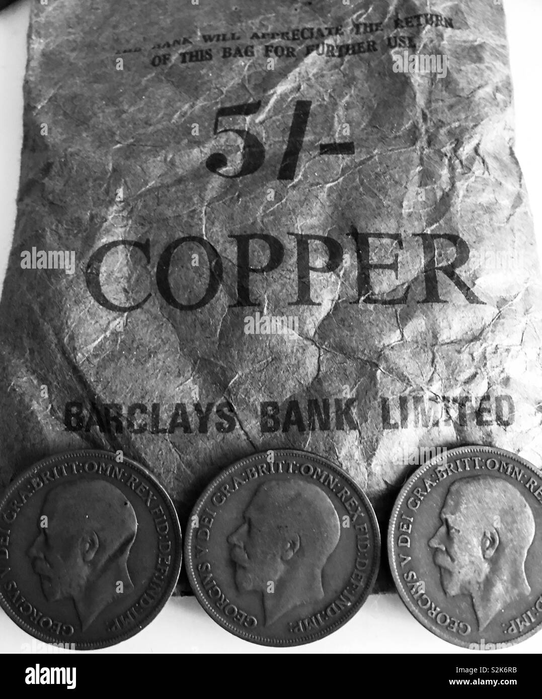 Old George V Penny coins on a paper bank bag for copper coins Stock Photo
