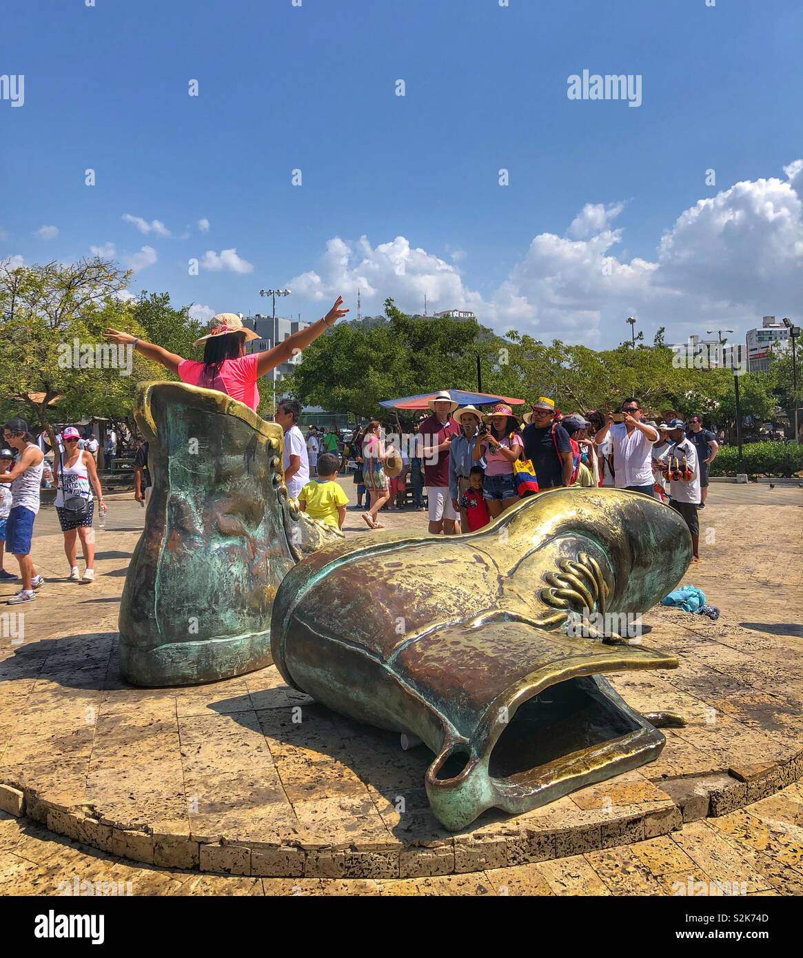 Tourists line up to pose in a sculpture of large bronze boots in Cartagena, Colombia. - Smartphone Captured Stock Image