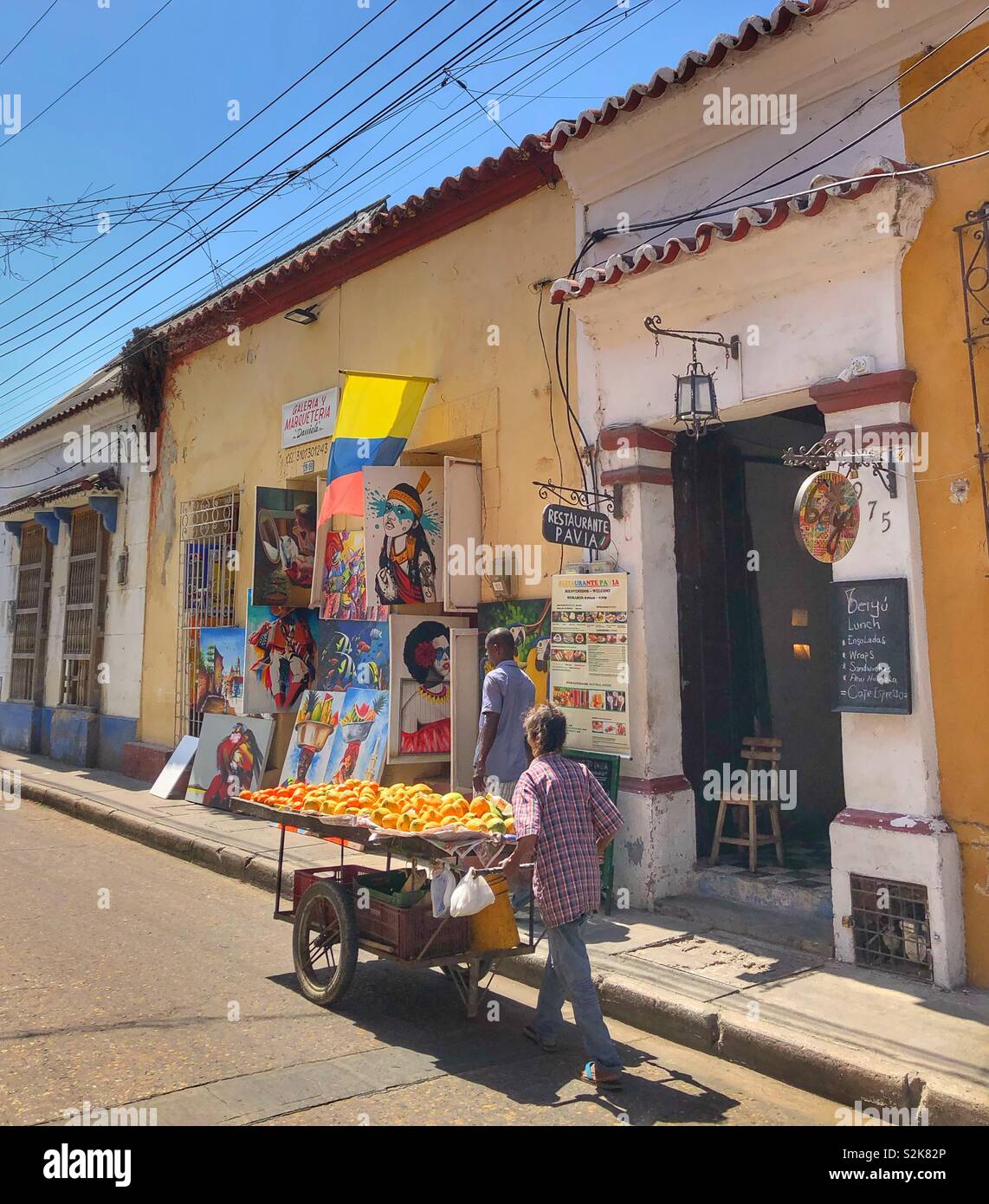 A fruit street vendor pushing his cart down a street in the Getsemani neighbourhood in Cartagena, Colombia. - Smartphone Captured Stock Image