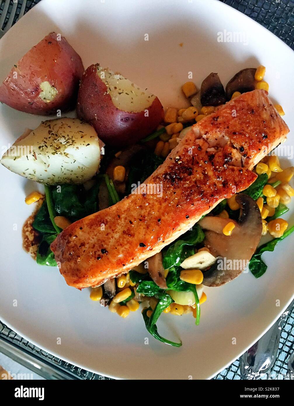 Gourmet meal of seared salmon fillet on a bed of fresh spring vegetables, USA - Smartphone Captured Stock Image