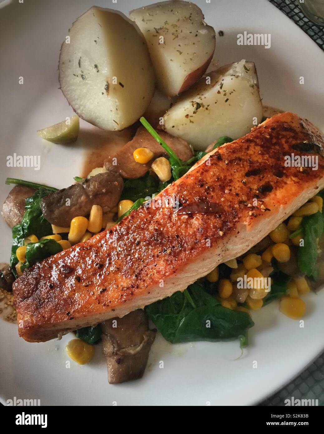 Gourmet meal of seared salmon fillet on a bed of fresh spring vegetables and potatoes, USA - Smartphone Captured Stock Image