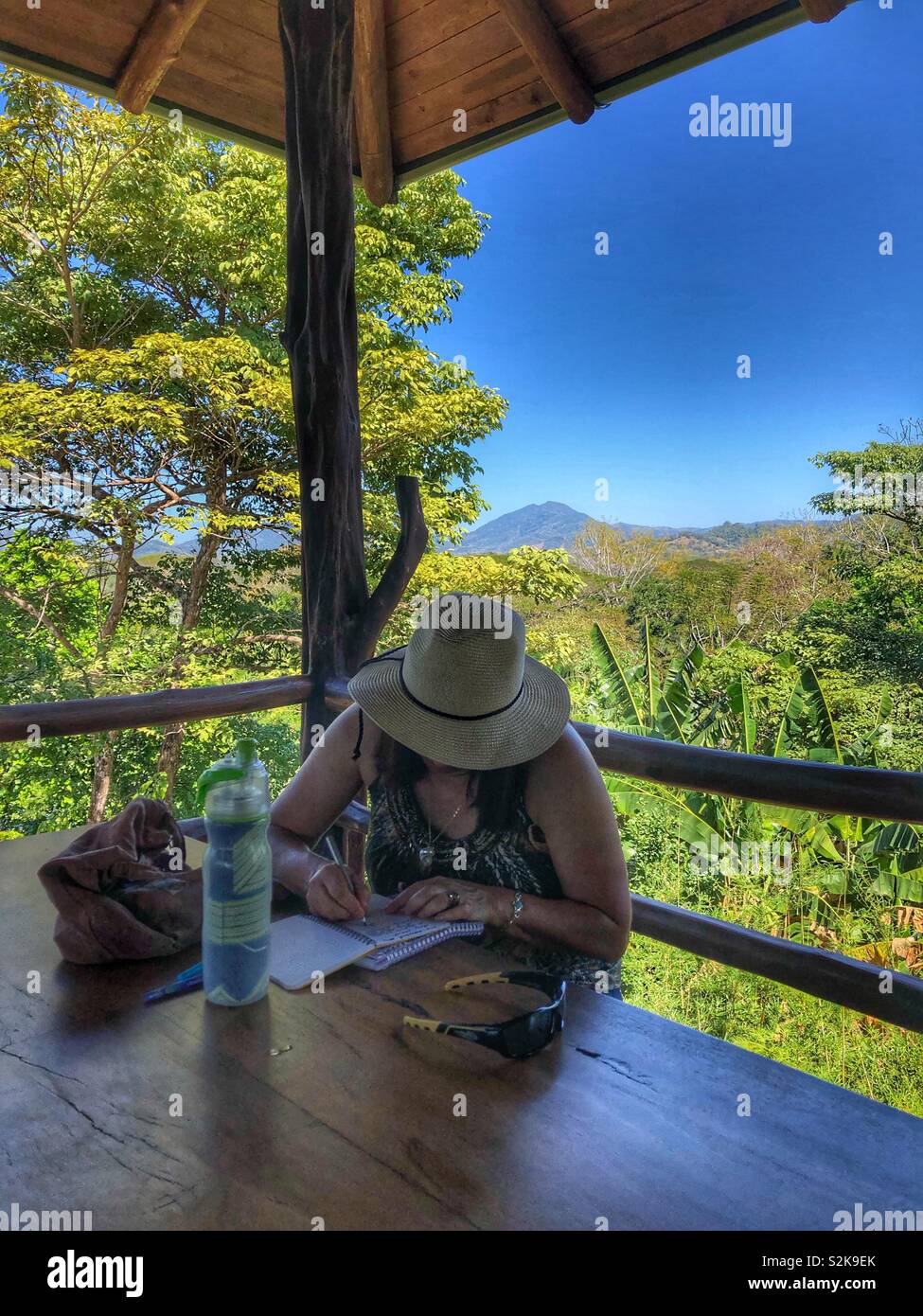 A woman writing in her journal surrounded by beautiful scenic nature. - Smartphone Captured Stock Image