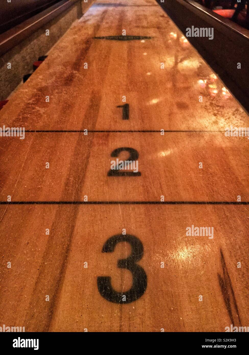 Player’s end of a hand shuffleboard game board with the numbers 1, 2, and 3 painted on it. - Smartphone Captured Stock Image