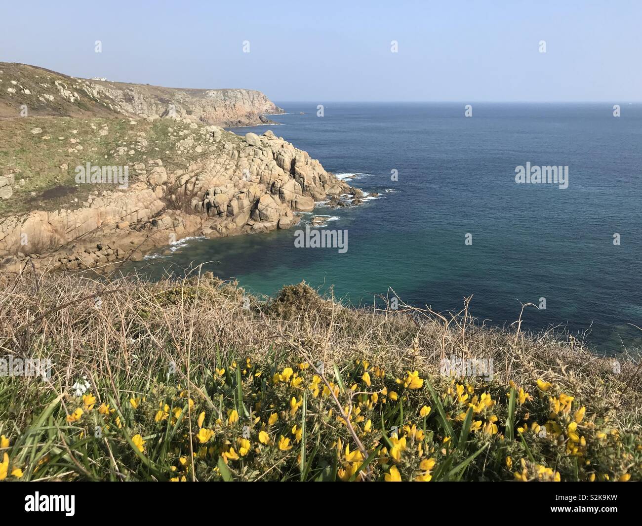 Spring day at Porthgwarra with gorse in foreground, Cornwall, England, UK Stock Photo