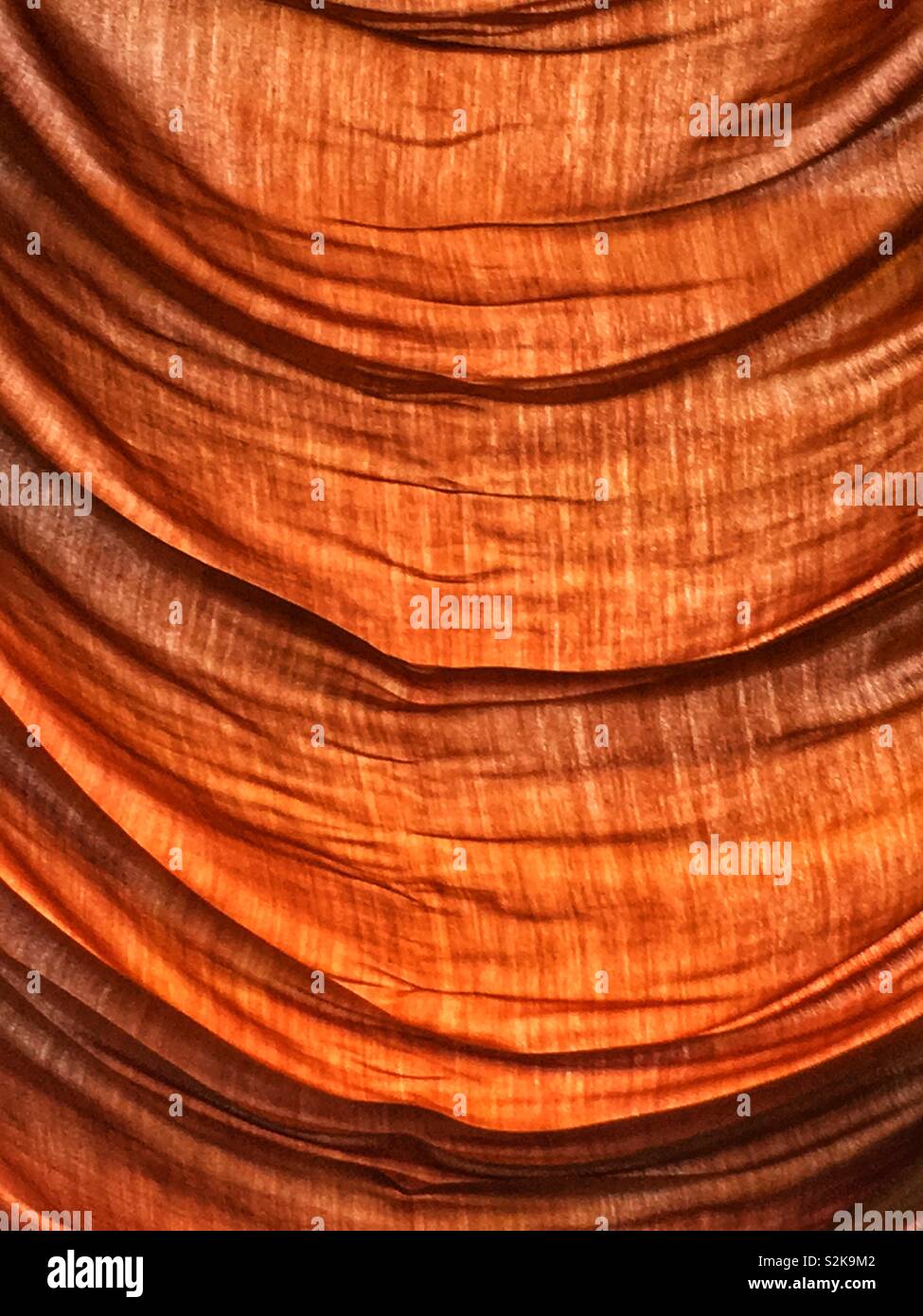 Orange beige silk drapery draped across the full frame picture. Stock Photo