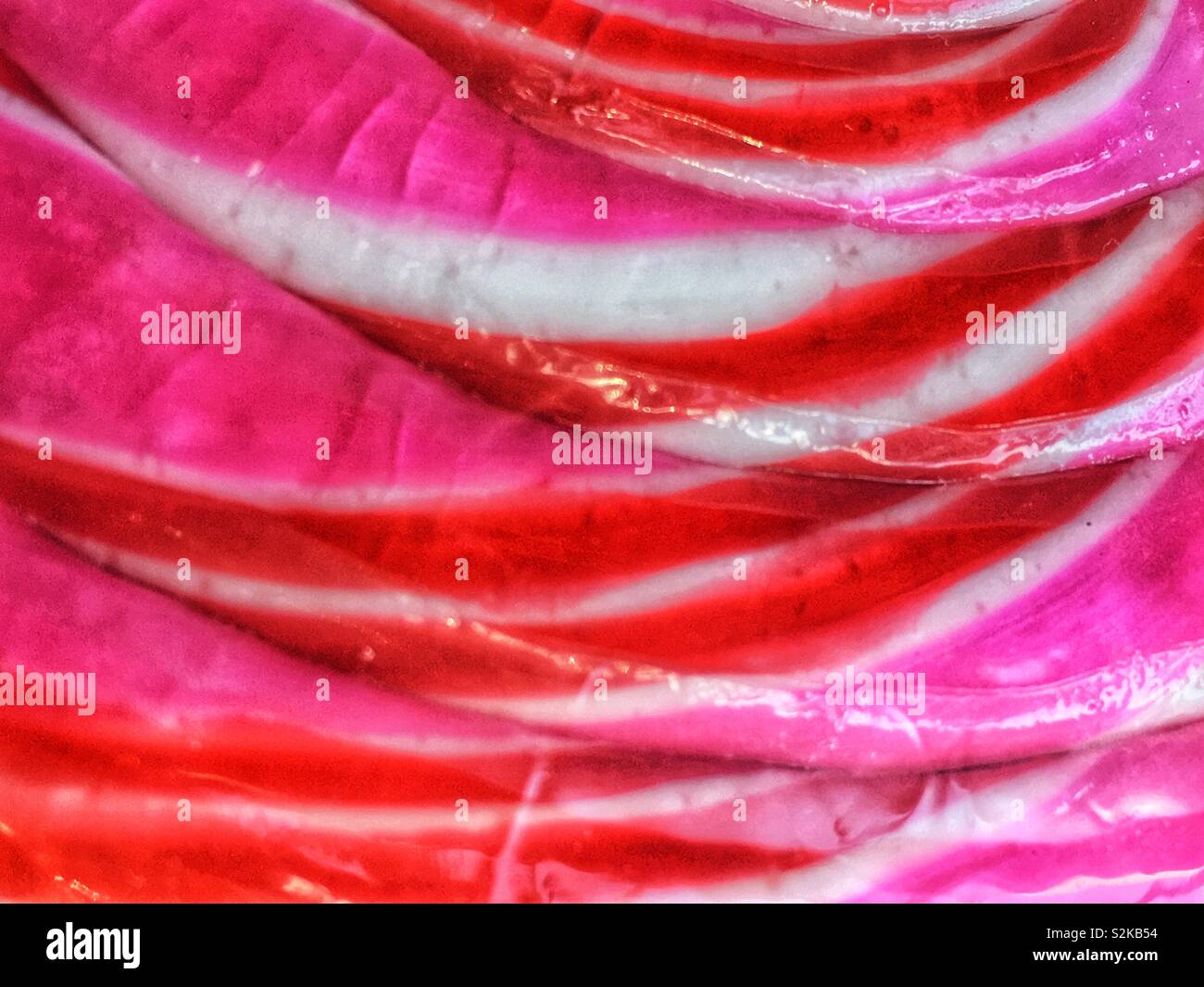 Full frame of a delicious fresh pink, red and white swirled hard candy lollipop. - Smartphone Captured Stock Image
