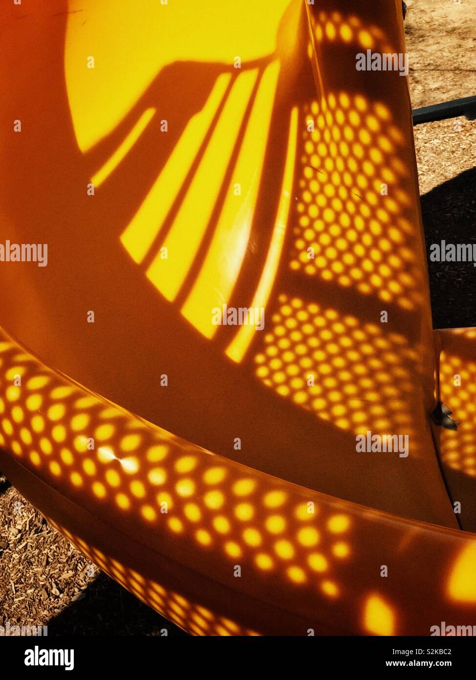 shadowed yellow spiral sliding board at the playground Stock Photo