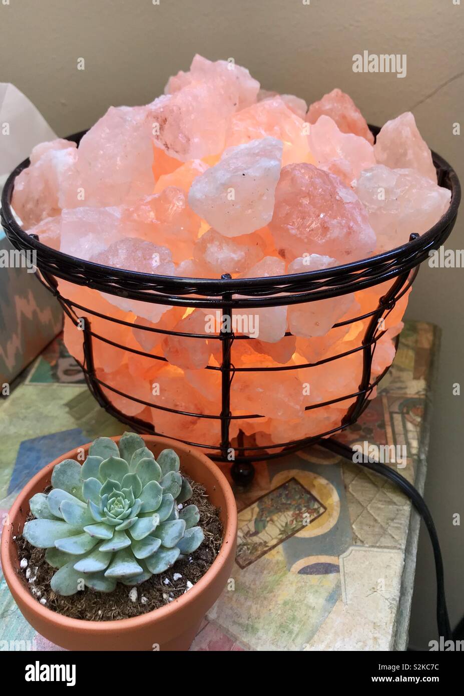 Himalayan salt rock lamp basket and succulent plant on decoupage table stand Stock Photo