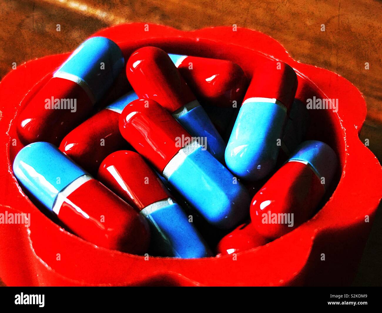 Closeup of red and blue generic pills in a plastic red container - Smartphone Captured Stock Image