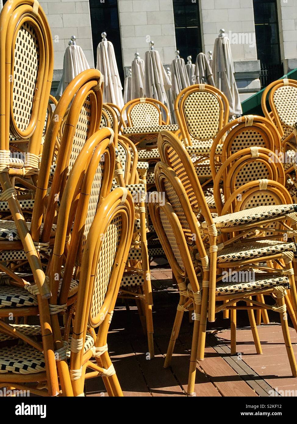Stacks of wicker wooden chairs and I’m Barela’s awaiting the opening of an outdoor café in Bryant Park, NYC, USA - Smartphone Captured Stock Image