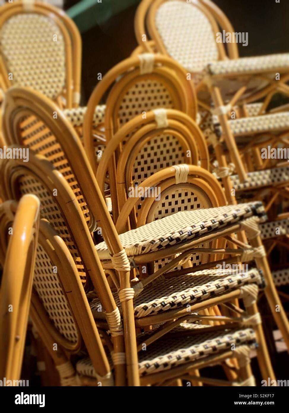 Stacks of wood and wicker chairs waiting the opening of an outdoor café in Bryant Park, NYC, USA - Smartphone Captured Stock Image