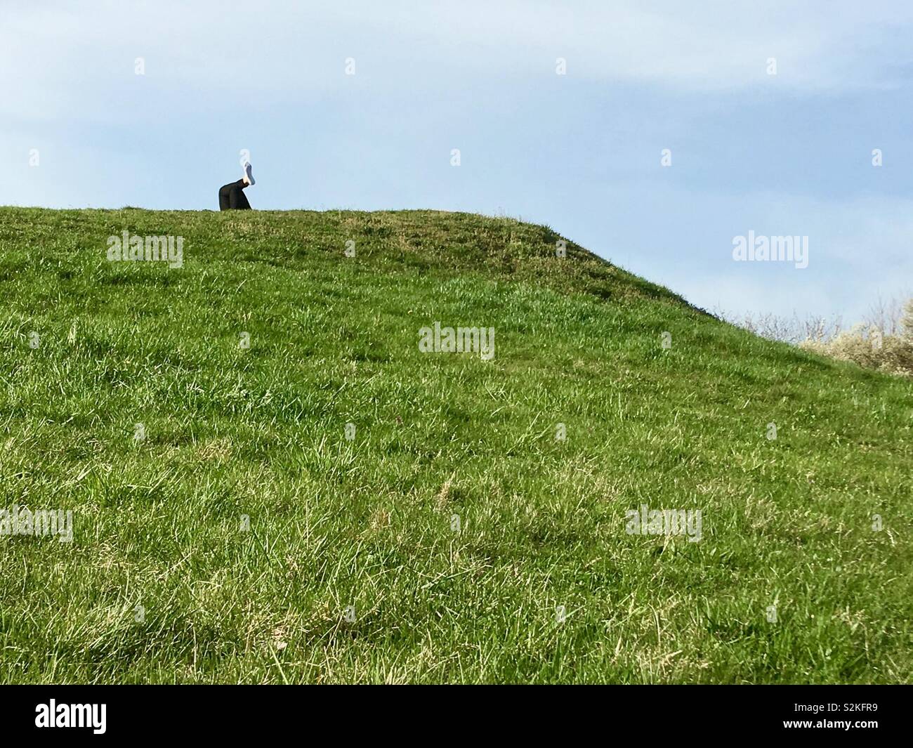 Only the leg of a sunbathing person appears on the hill top shot from below - Smartphone Captured Stock Image